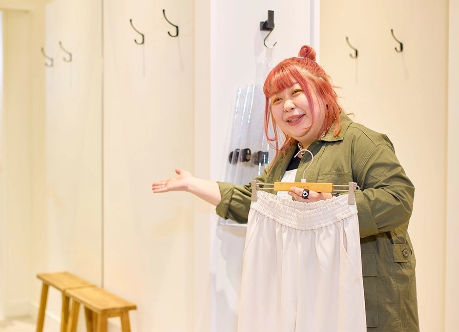 アパレル販売スタッフ（アルバイト・パート）のS.A.さんが試着室を案内している様子